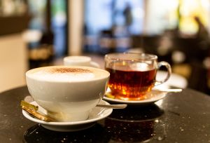 Großer Cappuccino mit deftiger Milchhaube und ein heißer, klarer Tee zum Verzehren bereit