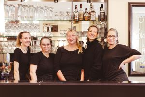 Teamfoto von fünf Mitarbeiterinnen hinter der Theke