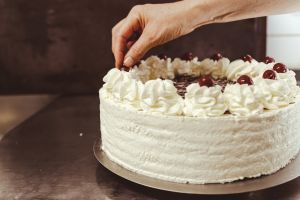 Hand die eine hausgemachte Torte mit einer Kirsche graniert