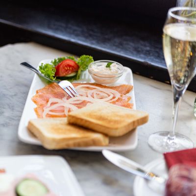 Rosige Räucherlachsstreifen serviert mit dünnen Zwiebelringen, Salat, Dip and knusprigem Toast
