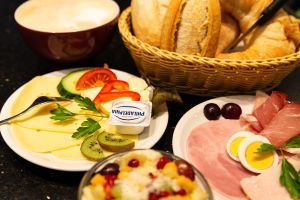 Ein Botkorb, ein Kaffeegetränk eine kleine Schüssel Obstsalat und Teller mit Wurst und Käse